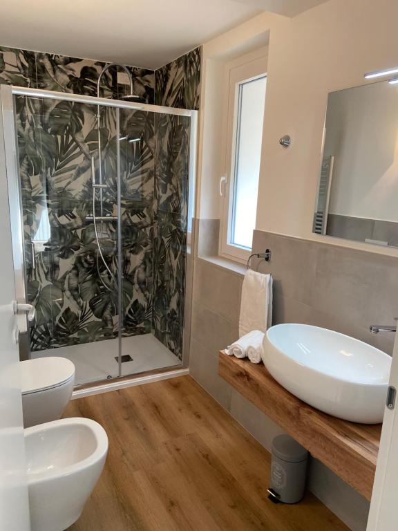 Bagno con doccia, parete decorata e lavabo d’appoggio